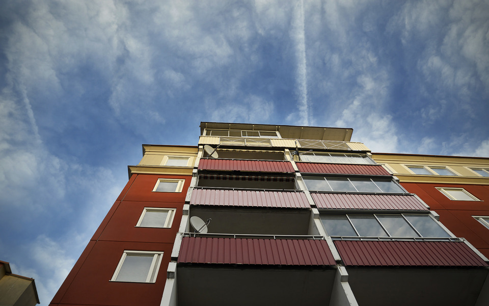Blå himmel med moln med rödaktig fasad med flerfamiljshus.